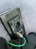 A long green cord is firmly plugged into an electrical outlet, allowing it to connect and provide power to various devices or appliances that require an electrical source photo