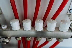 This detailed and upclose view showcases a heating system that prominently features vibrant red pipes, alongside white protective caps designed to safeguard the various system components photo