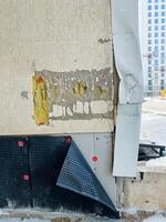 In a corner of a building, theres a drain pipe protruding, illustrating the use of various construction elements and materials surrounding it, like concrete, paint, and prominent shadows photo