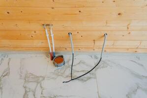 A disorganized bunch of wires is carelessly laying on the floor right next to a sturdy wooden wall, creating a cluttered atmosphere within the space that needs attention photo
