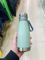 A person is currently holding a green water bottle in their hand, showcasing a vibrant color that stands out in any setting, making it easy to identify and use for hydration purposes photo