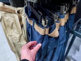 A person is carefully reaching into a pocket of a stylish and comfortable pair of denim pants, perhaps looking for something they need or have misplaced within the pocket photo