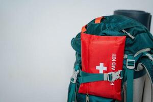 A bright red first aid kit is conveniently attached to a durable and sturdy backpack, ensuring easy access to essential medical supplies that can be used for various everyday emergencies photo