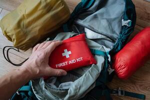 A person is firmly holding a bright red first aid kit, which is an essential item used during emergencies to provide immediate medical assistance when it is urgently needed photo