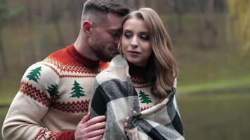 Man hugging his girlfriend in plaid standing behind her. Romantic date in the countryside near the river. Lovely couple at the backdrop of autumn nature. video