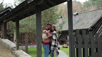 Couple in love standing at the gates of a rural complex. Happy couple hugging near the country house gates. Pair in warm sweaters enjoying autumn in the village. video