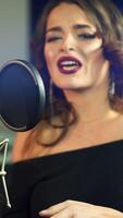 young singer is singing and recording a song in the audio studio on a blue background. Close-up Vertical video