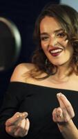 expressive woman with curly hair is singing and dancing in front of a microphone in an audio recording studio on a blue background. Close-up Vertical video
