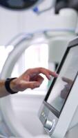 Unrecognized doctor switching on the equipment in modern surgical theatre. Specialist pressing the keys on the sensor screen. Side view. Vertical video