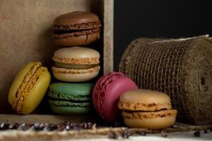 View of small multi-colored macaroons in a wooden box on a dark background photo