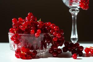 View of bunches of red currants in a glass goblet on a black background photo