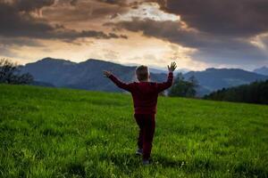 little boy runs in the rays of the sunset, hiking in the mountains photo