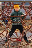 View of a child climbing an alpine net in a park on a playground on a spring day photo