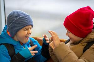 Two boys have fun while traveling in public transport near the window photo