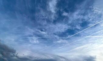 View of aircraft contrails and cloud clouds against blue sky photo