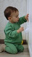 Toddler standing on his knees on the floor trying to open the closet. Kid fails and cries and then tries again. Vertical video