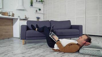Man using laptop at home. Handsome man using laptop while lying on the floor video