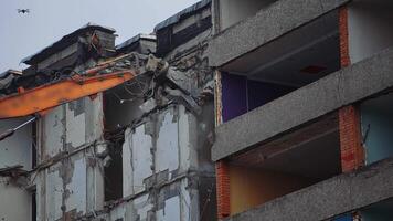 excavadora garra agarrar el hormigón pared en orden a descanso él. demoledor el edificio destrozado por un terremoto. ver desde abajo. video