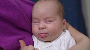 Baby doesn't want to wake up and barely opens his eyes. Mother is touching baby's nose gently to wake him up. Close up. video