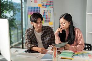 Diverse graphic design team analyzing project details and color schemes in a modern workspace. photo