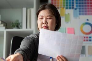 Diverse graphic designer selecting color swatches for a project in a workspace. photo
