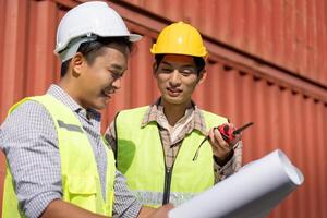 Engineers discussing logistics and construction plans with blueprints and a walkie-talkie. photo