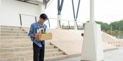 Man departing from workplace with a box of belongings, representing a significant career transition. photo