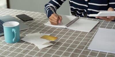Individual calculating income and bills at home with notebook and calculator photo