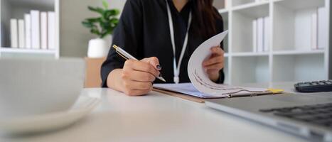 Detail-oriented financial expert reviewing documents and making calculations in a modern office. photo