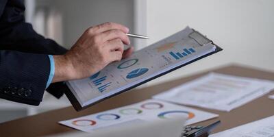 Professional analyzing financial charts and graphs with a pen, focusing on strategic business insights. photo