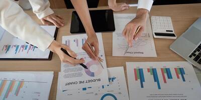 Hands of professionals pointing at financial charts and discussing strategies in a meeting. photo