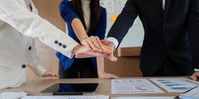 Diverse colleagues placing hands together in a show of teamwork and unity at a business meeting. photo