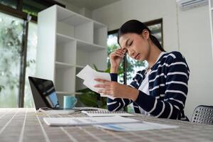 Young woman feeling stressed while managing bills and finances at home. photo