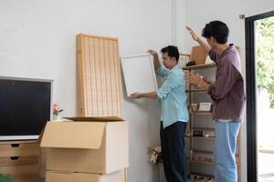 LGBTQ couple unpacking and arranging furniture in their new home, showcasing teamwork and love. photo