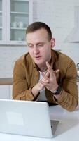 Young businessman having a conversation at home. Student speaking in front of a wireless laptop on kitchen background. Remote job. Vertical video