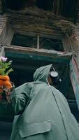 Ecologist in ruined building. Person in protective suit and gas mask with bunch of flowers. Air pollution in chemical zone. View from below. Vertical video
