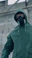 Man in gas mask on destroyed building background. Survivor in respirator and safety suit standing in radioactive zone. Ecological catastrophe. Post apocalyptic world. Vertical video