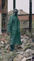 Survivor in destructed place. Human in protective clothing and respirator standing on a pile of garbage in abandoned place. High level of radiation. Vertical video
