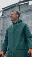 Happy ecologist in abandoned place. Man survivor holding gas mask in hands and smiles breathing fresh air on the background of destroyed building. Vertical video