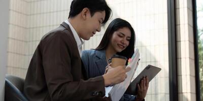 Diverse business team analyzing project plans and discussing strategies with coffee in modern office. photo