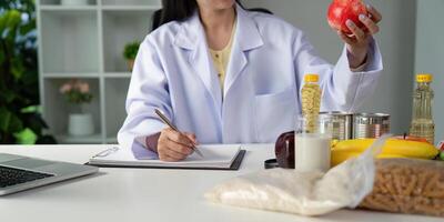 Nutritionist holding an apple while taking notes, emphasizing healthy eating during a meal planning session. photo