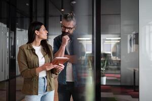 Creative millennials, casual business team, small business owners, working on social media strategy and brand development with a digital tablet in a modern, open space startup office photo