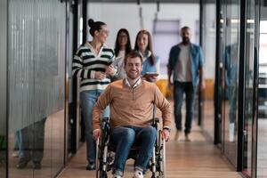 A businessman with disability in a wheelchair is surrounded by supportive colleagues in a modern office, showcasing the strength of teamwork, inclusivity, and empowerment in the face of challenges. photo