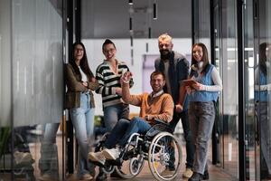 A businessman with disability in a wheelchair is surrounded by supportive colleagues in a modern office, showcasing the strength of teamwork, inclusivity, and empowerment in the face of challenges. photo