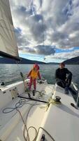 Father instructing daughter on sailing a yacht during training in the Kotor Bay, Montenegro, highlighting family bonding, adventure, and nautical sport. High quality 4k footage video