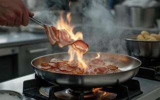 A chef skillfully flips slices of bacon in a frying pan over high heat, creating flames and smoke in a busy kitchen setting. The atmosphere is vibrant and filled with cooking activity photo