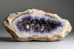 The stunning amethyst geode features a rough exterior with a vibrant interior filled with sparkling purple crystals, creating a captivating visual effect in subtle lighting photo