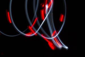A photo with a long shutter speed of two lights moving. One light is white and one is red. The red one has flashed.