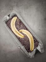Sliced bananas topping raw blueberry banana bread batter in parchment lined loaf pan, preparing for baking for Mother's Day Valentines copy space photo