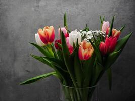 Vibrant bouquet of tulips adding a touch of color to a simple gray backdrop, celebrating the beauty of nature for Mother's Day Valentines copy space photo